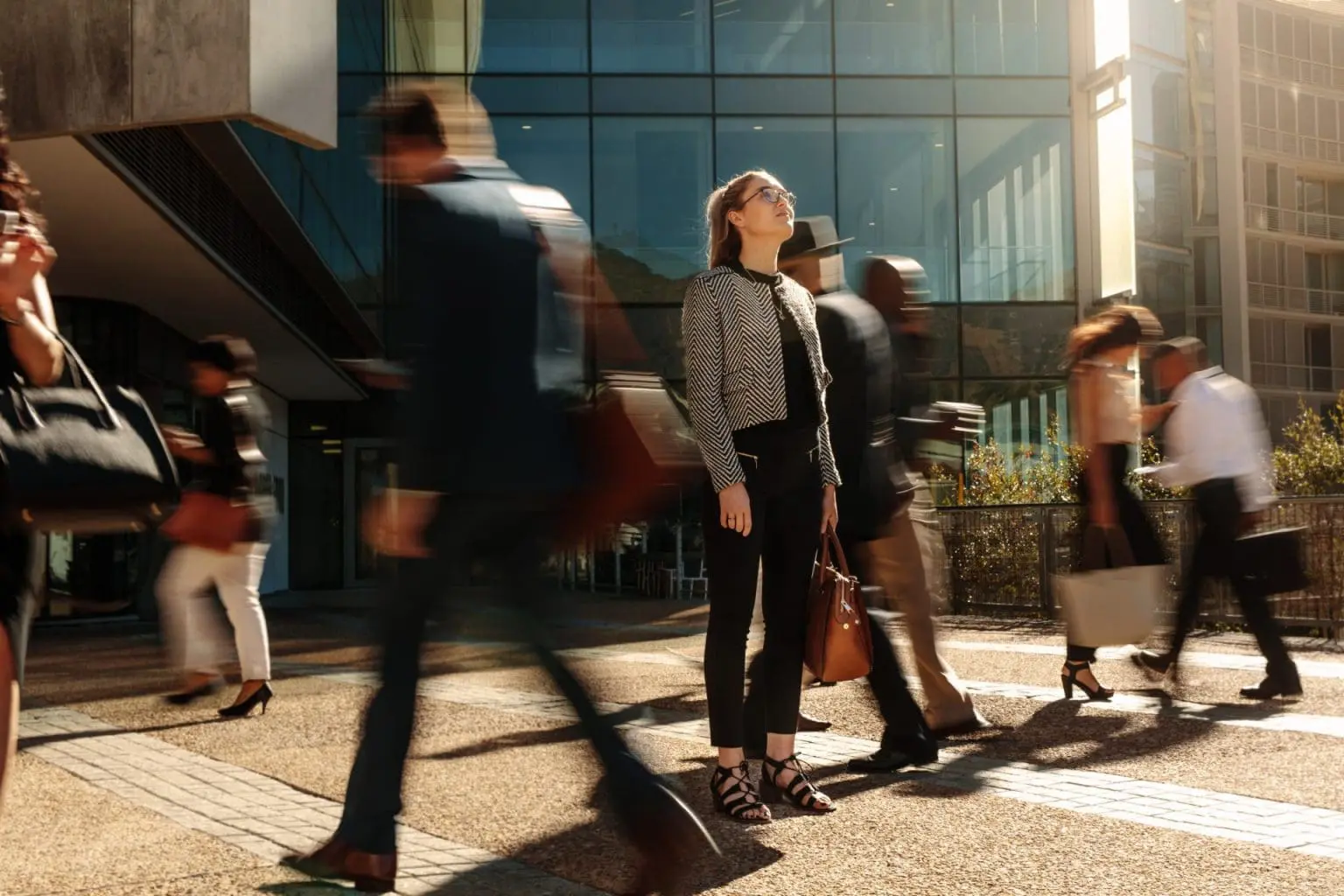 A female business traveler standing in front of an office building feeling safe due to her company's travel safety protocols.