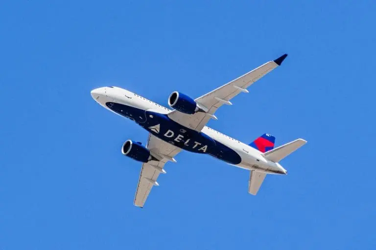 An airplane flying directly above with "DELTA" written on the bottom of the plane. August 1, 2019 Santa Clara / CA / USA - Delta Airlines aircraft in flight; the Delta Logo visible on the airplanes' underbelly; blue sky background